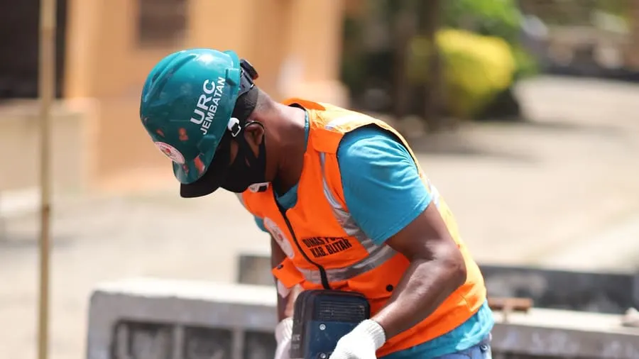 Trabajador de obra con casco y chaleco reflectante operando un martillo demoledor eléctrico sobre hormigón